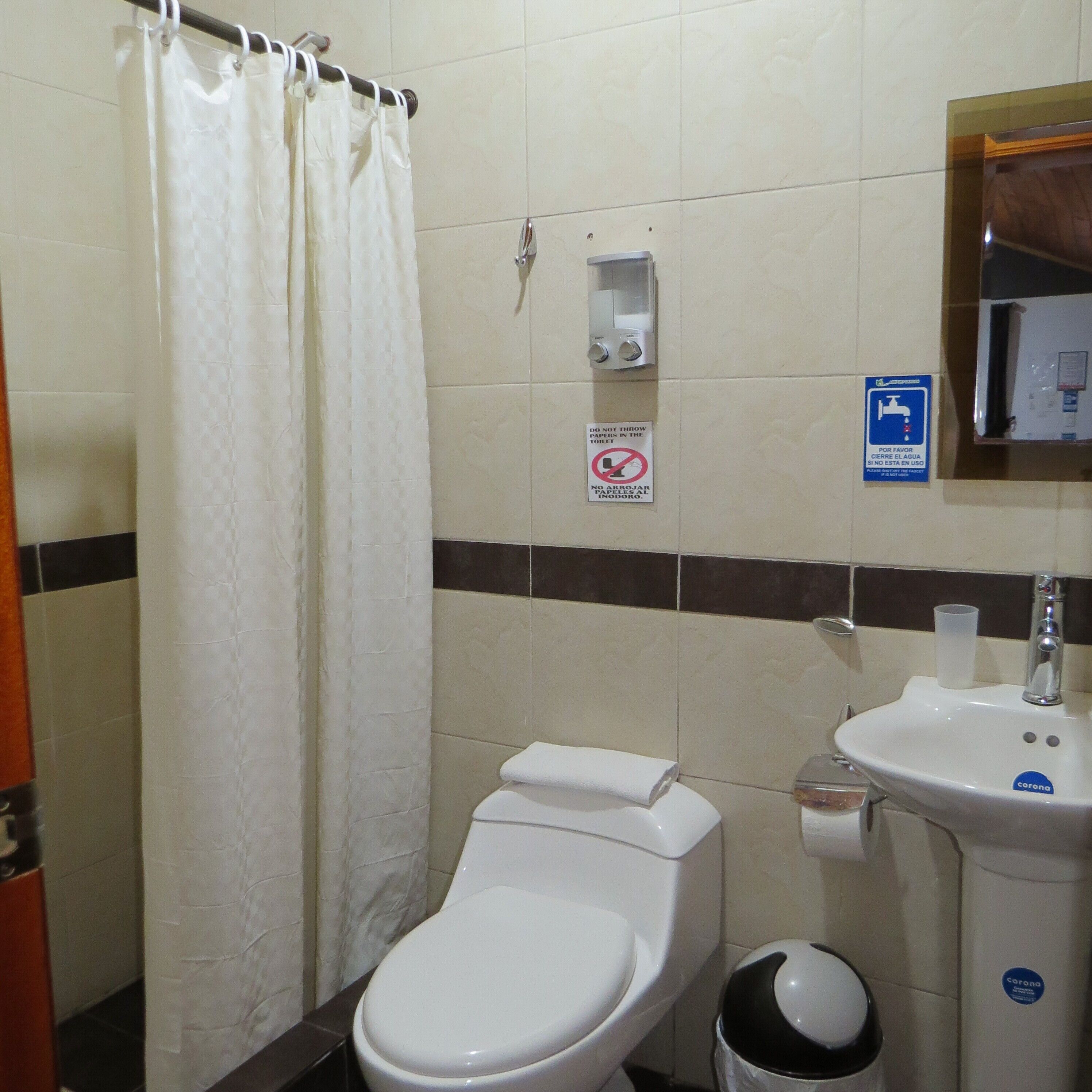 Un bagno con il water, un lavandino, un asciugatore di mani e un cestino.