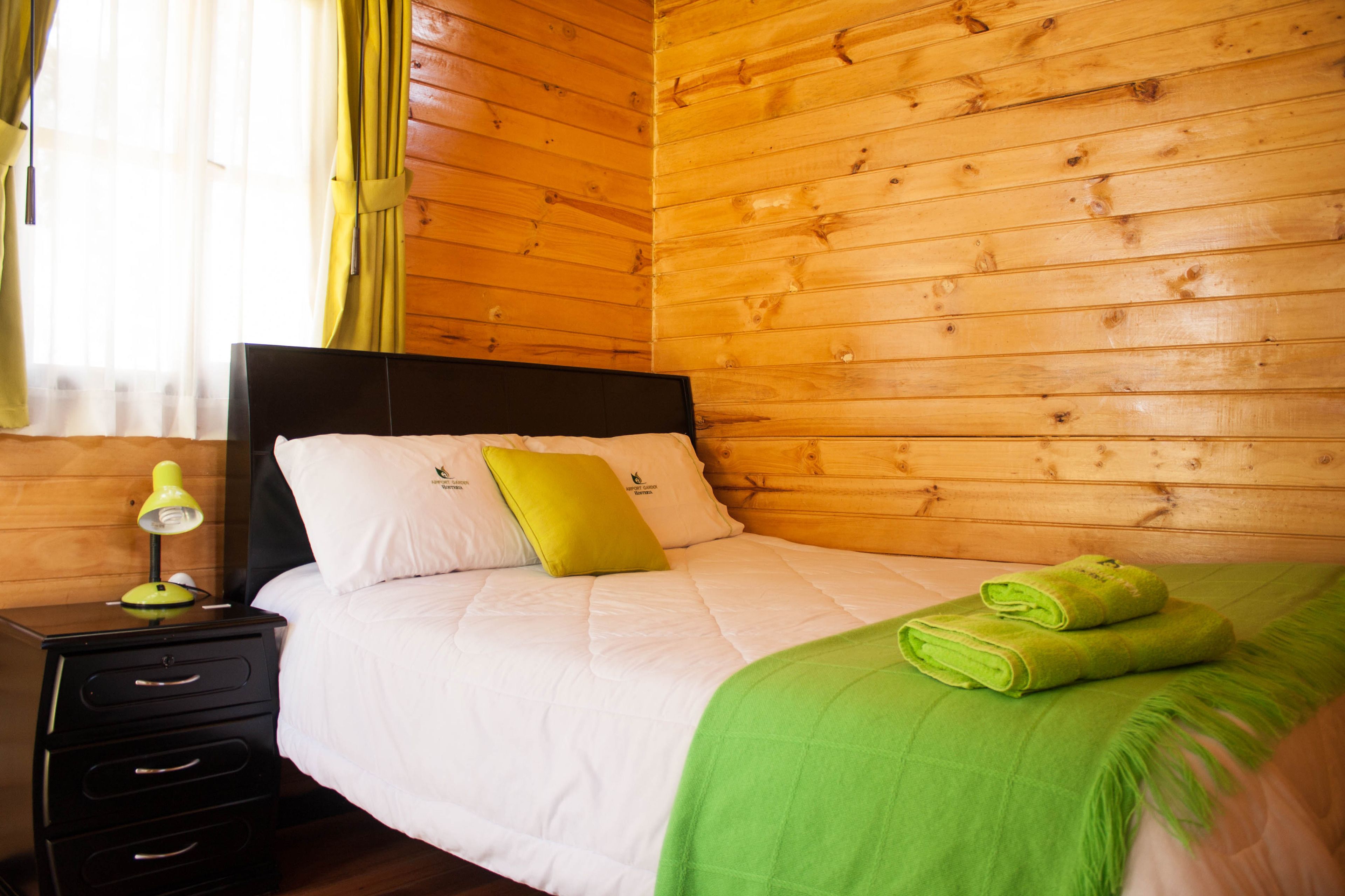 A wooden-paneled room with a bed, a nightstand, and a lamp.