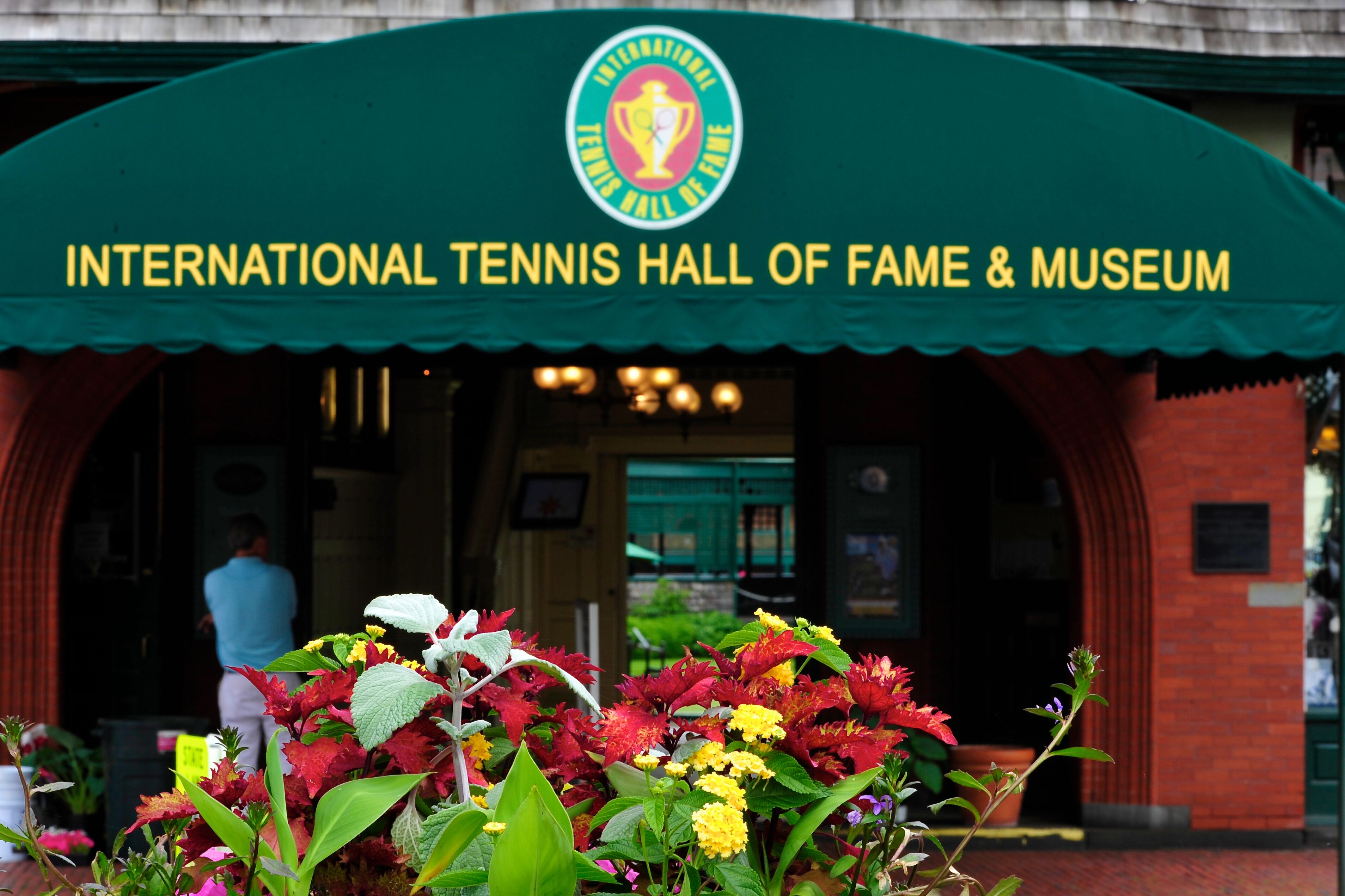 The entrance to the International Tennis Hall of Fame & Museum with a green arch and a sign.