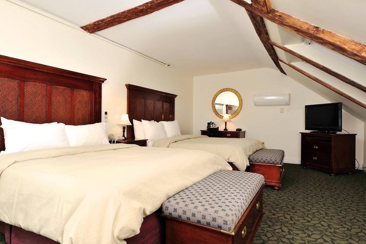 Une chambre d’hôtel avec deux lits, une télévision, un miroir et une commode.