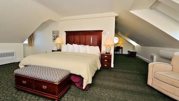 A hotel room with a large bed, a bench, a sofa, and a clock on the wall.