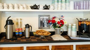 A buffet setup with coffee makers, Torani syrups, a cookie display, and a floral arrangement. - Jailhouse Inn (Newport)