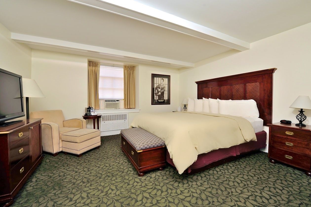 Una habitación de hotel con una cama grande, televisión, escritorio y una silla.