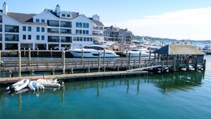 A marina with boats docked, a wooden pier, and multi-story buildings with balconies. - Harborside Inn (Newport)