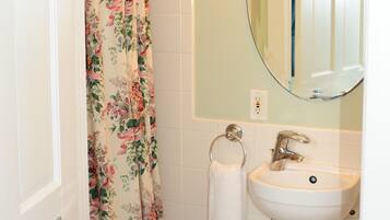 A bathroom with a shower curtain, a sink, a mirror, and a toilet.