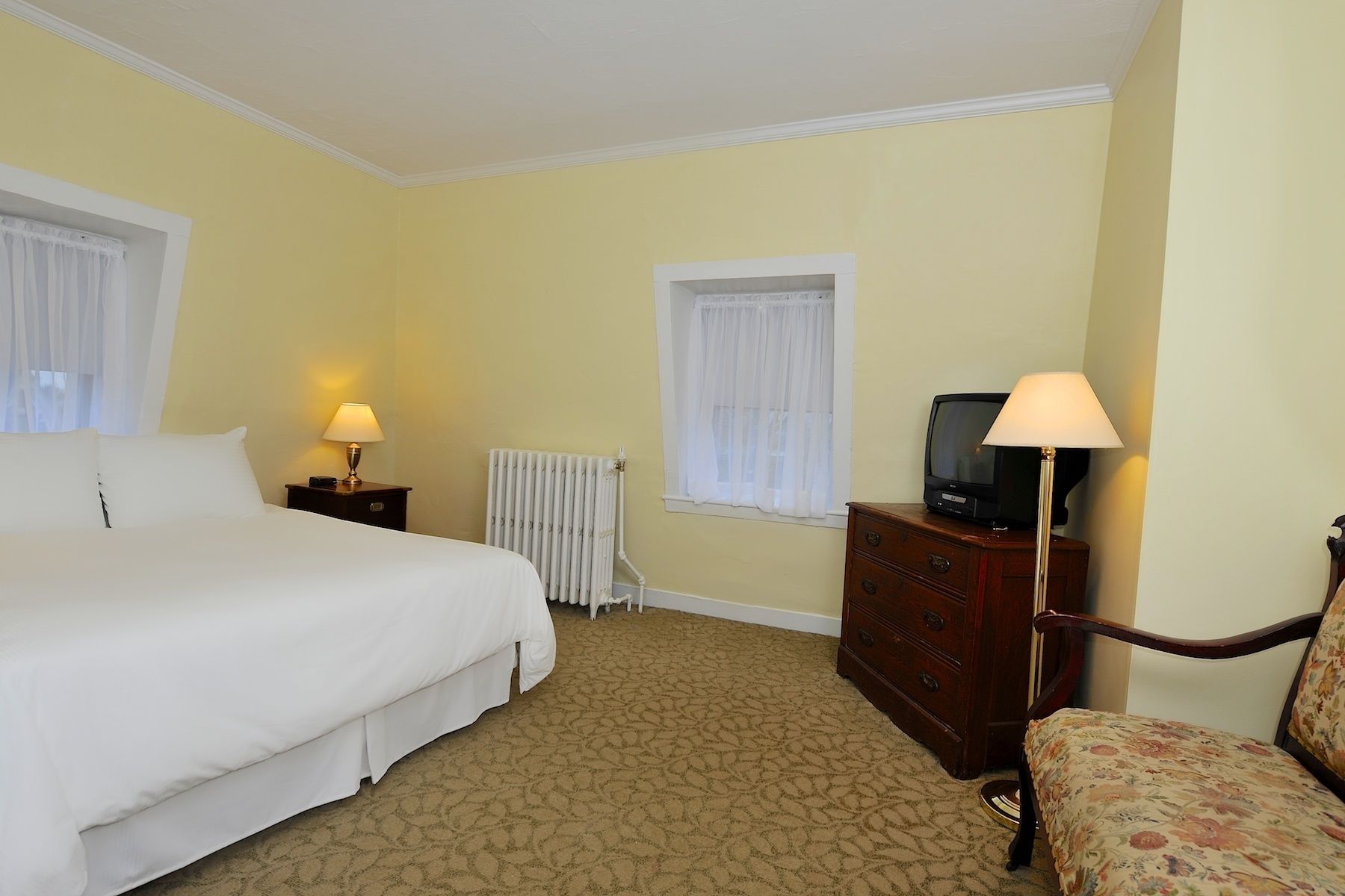 A hotel room with a bed, a dresser, a television, and a chair.