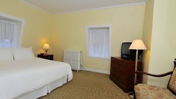 A hotel room with a bed, a dresser, a television, and a chair.