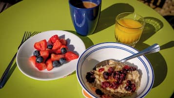 Ein Frühstücksbuffet mit Haferflocken, Beeren, Erdbeeren, Blaubeeren, Orangensaft und einer blauen Tasse.