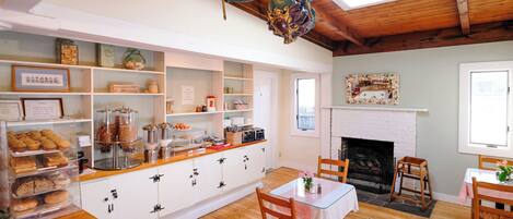 A cozy dining area with wooden flooring, a fireplace, and a table set for two.