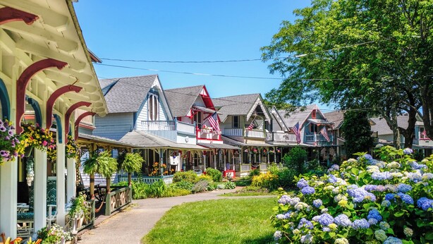 A row of traditional wooden houses with attached porches, a pathway, and lush greenery. - Pequot Hotel (Oak Bluffs)