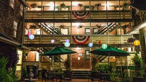 A two-story building with a balcony, outdoor seating area, and a fountain. - Pequot Hotel (Oak Bluffs)