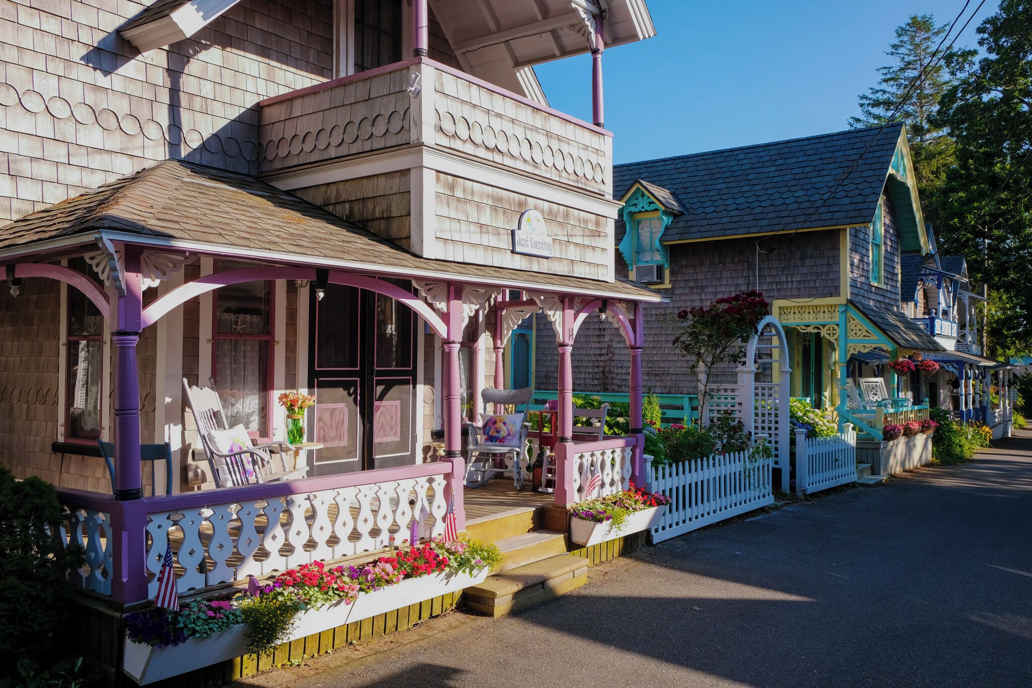 A two-story building with a porch, a picket fence, and flower boxes.