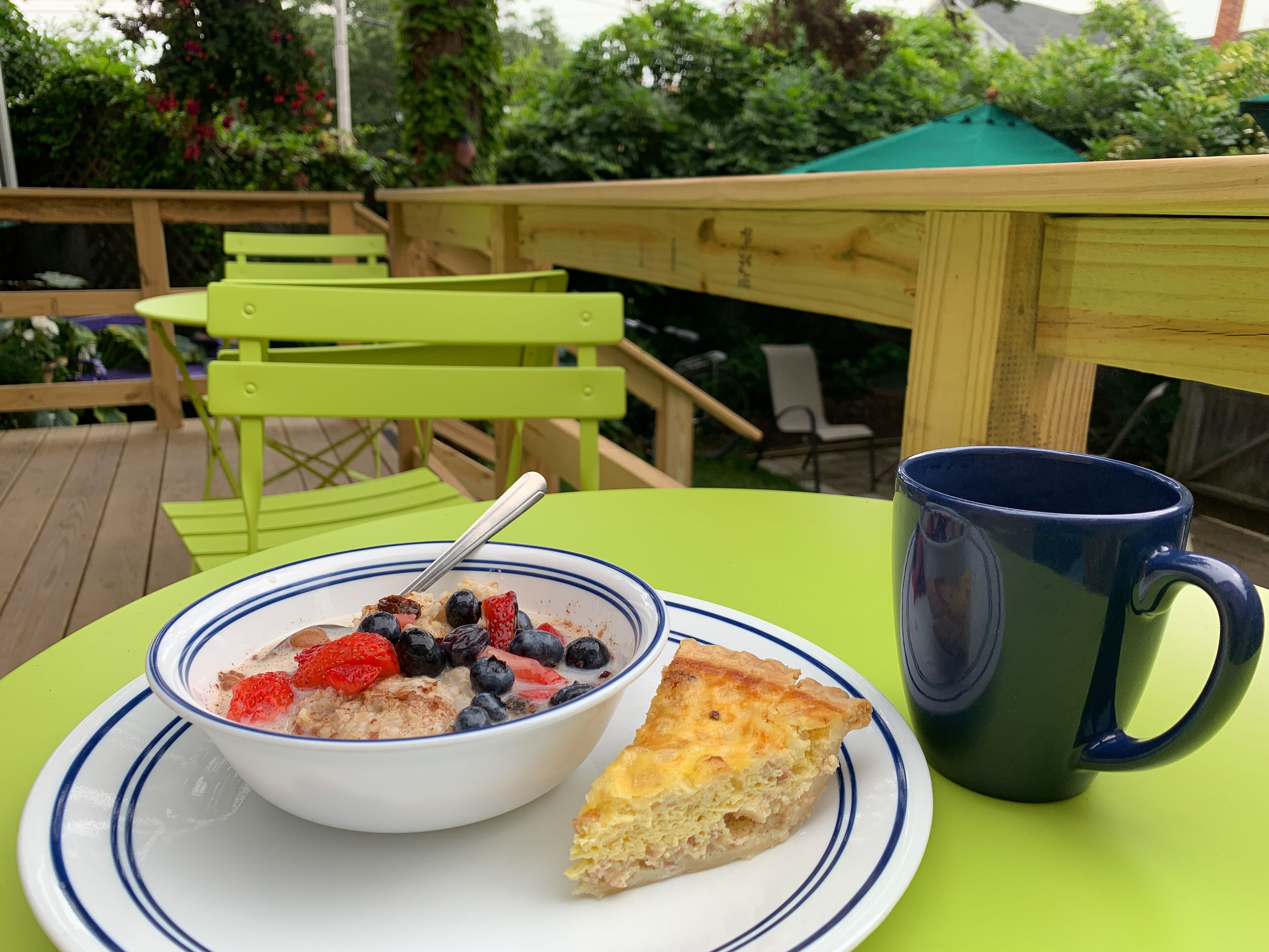 A table with a bowl of cereal, a slice of pie, and a mug.