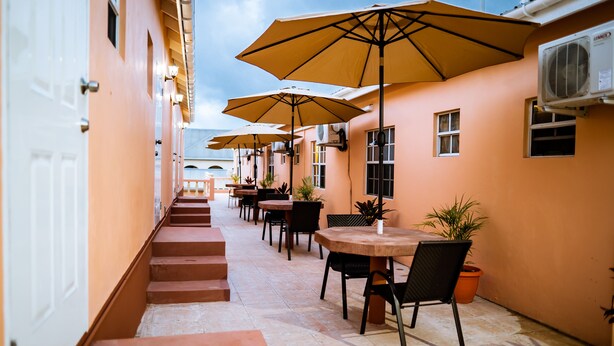 A corridor with outdoor seating, tables, chairs, and potted plants. - Connie's Comfort Suites (St. John's)