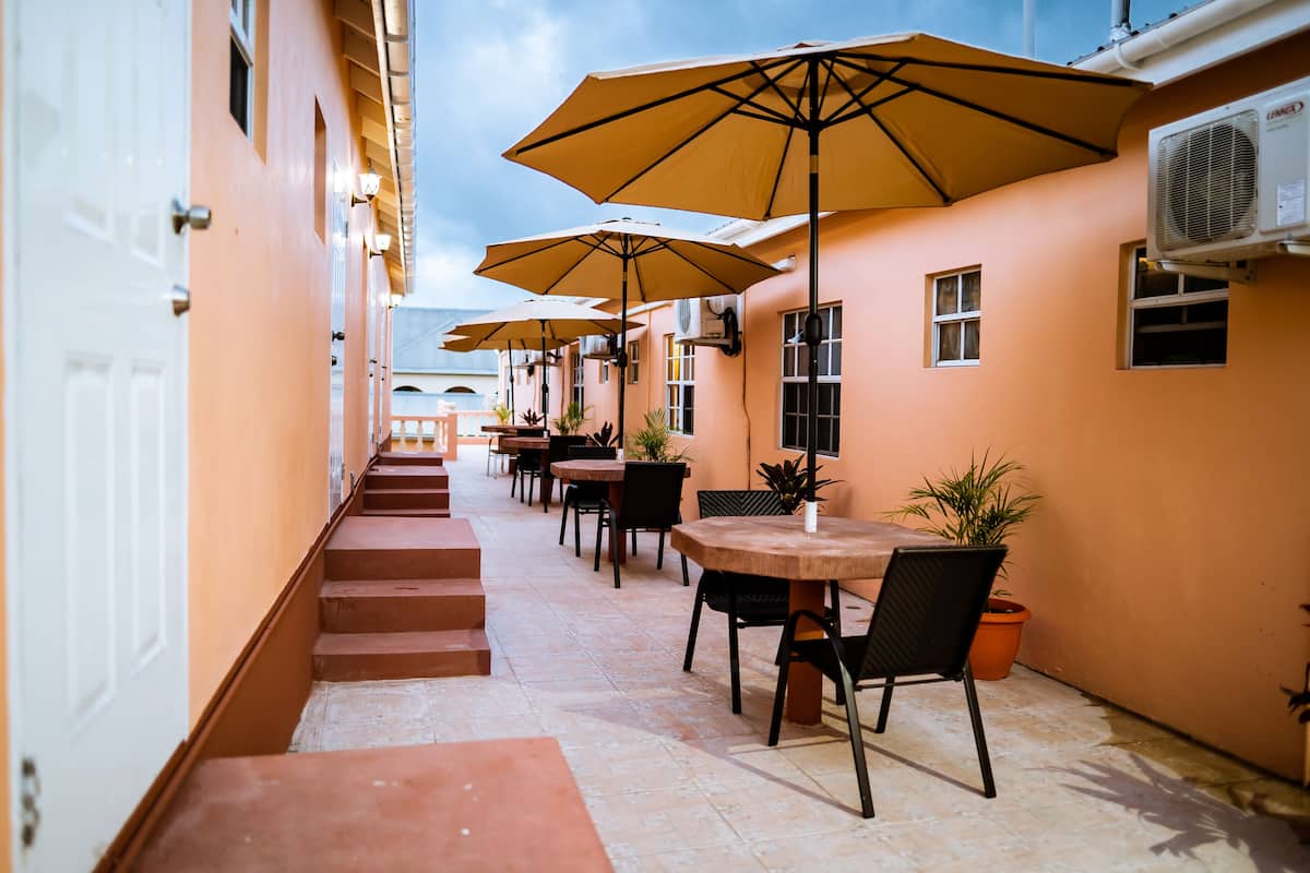 A corridor with outdoor seating, tables, chairs, and potted plants.