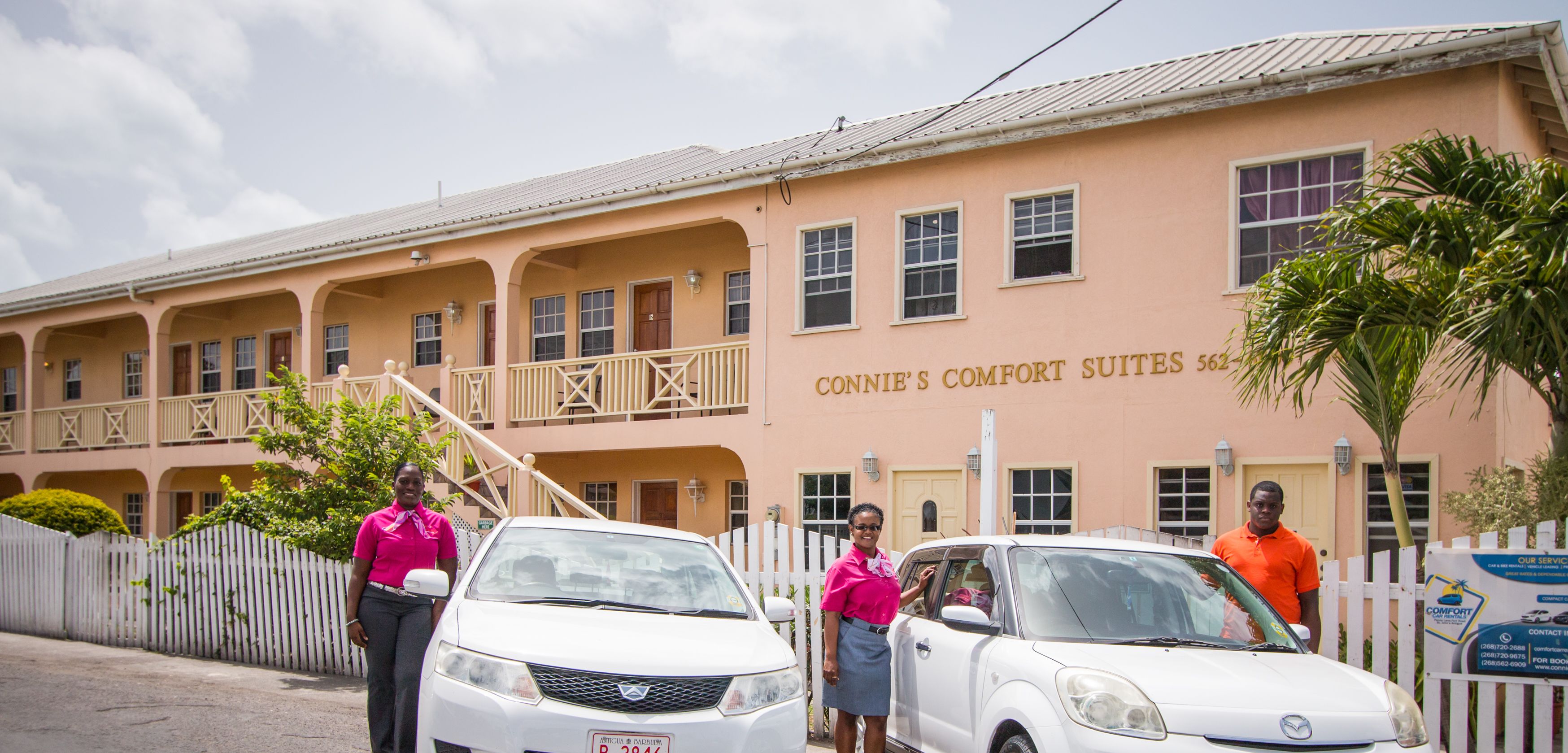 Ein Hotel mit mehreren Balkonen, einem weißen Zaun und einem Schild mit der Aufschrift "CONNIE'S COMFORT SUITES 562".