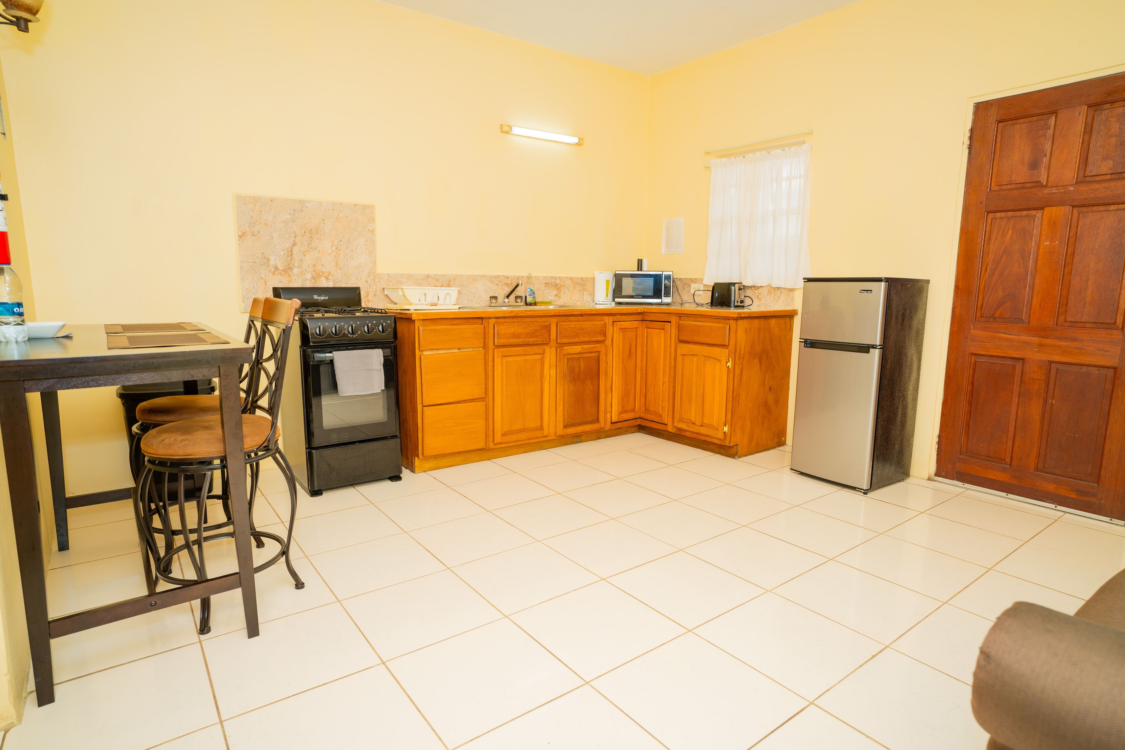 A kitchen with wooden cabinets, a stove, a microwave, and a refrigerator.
