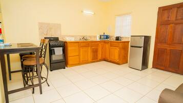 A kitchen with wooden cabinets, a stove, a microwave, and a refrigerator.