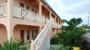 A multi-story building with a balcony, a staircase, and lush greenery. - Connie's Comfort Suites (St. John's)