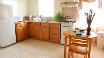 A kitchen with wooden cabinets, a white stove, a sink, and a dining table with chairs.