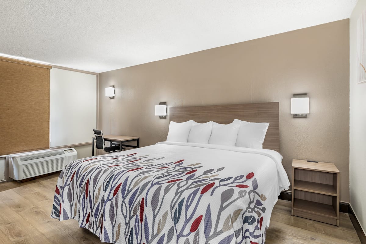 A hotel room with a large bed, two bedside tables, a desk, and a chair.