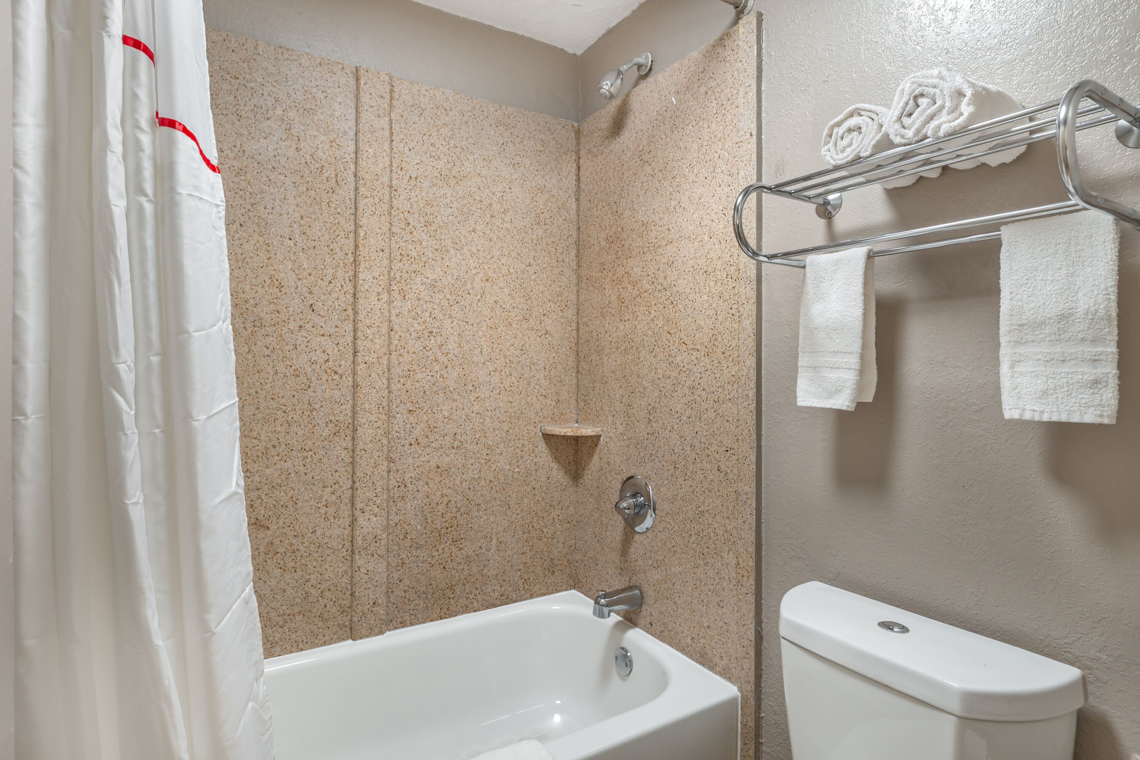 A bathroom with a bathtub, a toilet, and a shower area.