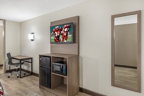 A hotel room with a flat-screen TV mounted on the wall, a compact refrigerator, a microwave, a wooden cabinet, a chair, and a large mirror. - Red Roof Inn Richmond, VA (Richmond)