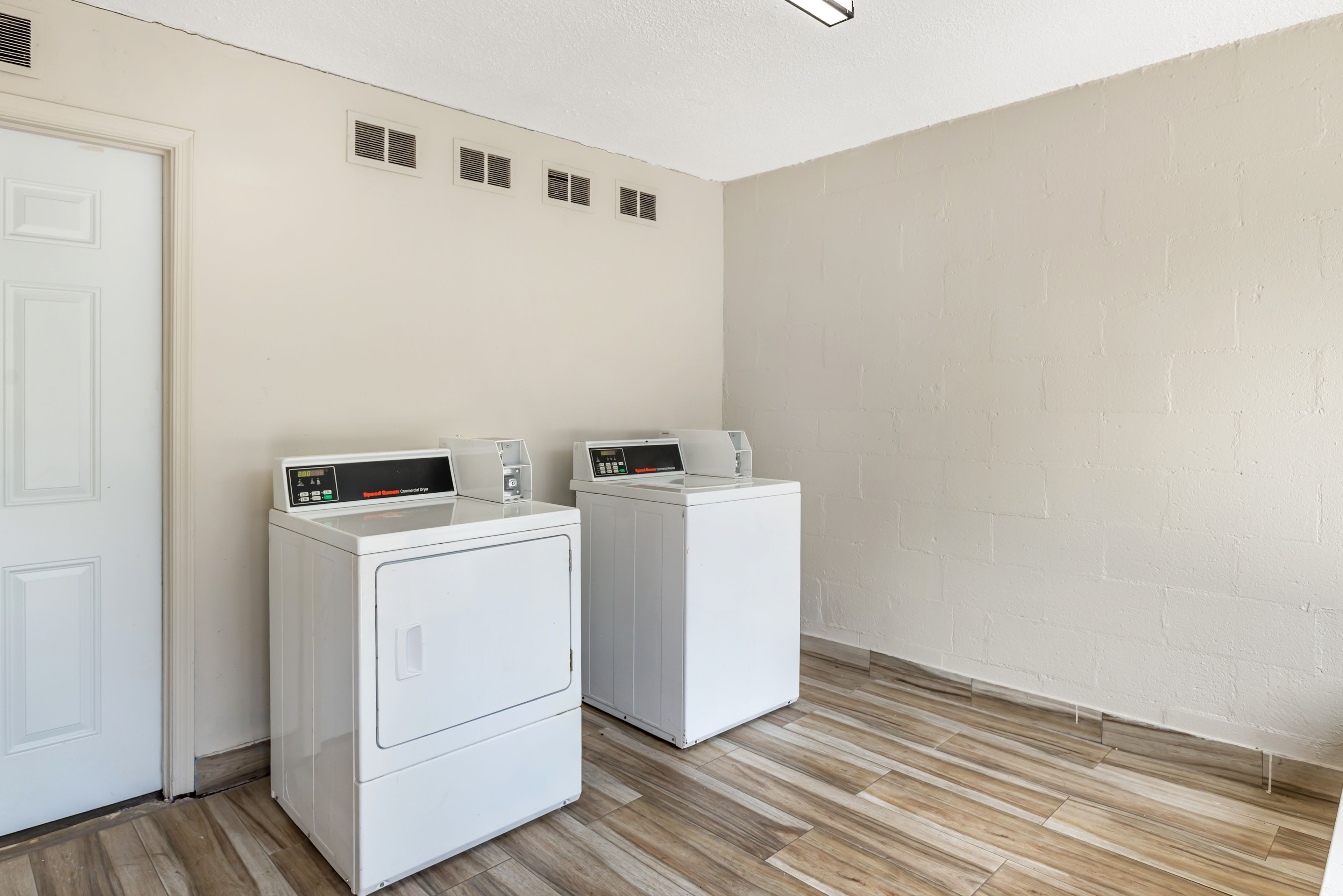 A laundry room with two white front-loading washing machines and a white door.
