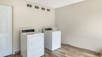 A laundry room with two white front-loading washing machines and a white door.
