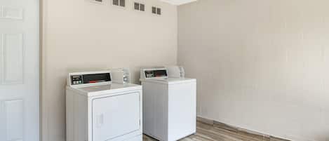 Une buanderie avec deux machines à laver à chargement frontal blanches et une porte blanche.