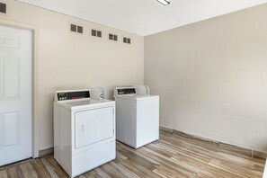 Une buanderie avec deux machines à laver à chargement frontal blanches et une porte blanche.