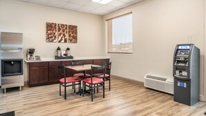 A kitchenette with a refrigerator, coffee maker, and a microwave. There is a dining area with a table and chairs. - Red Roof Inn Richmond, VA (Richmond)