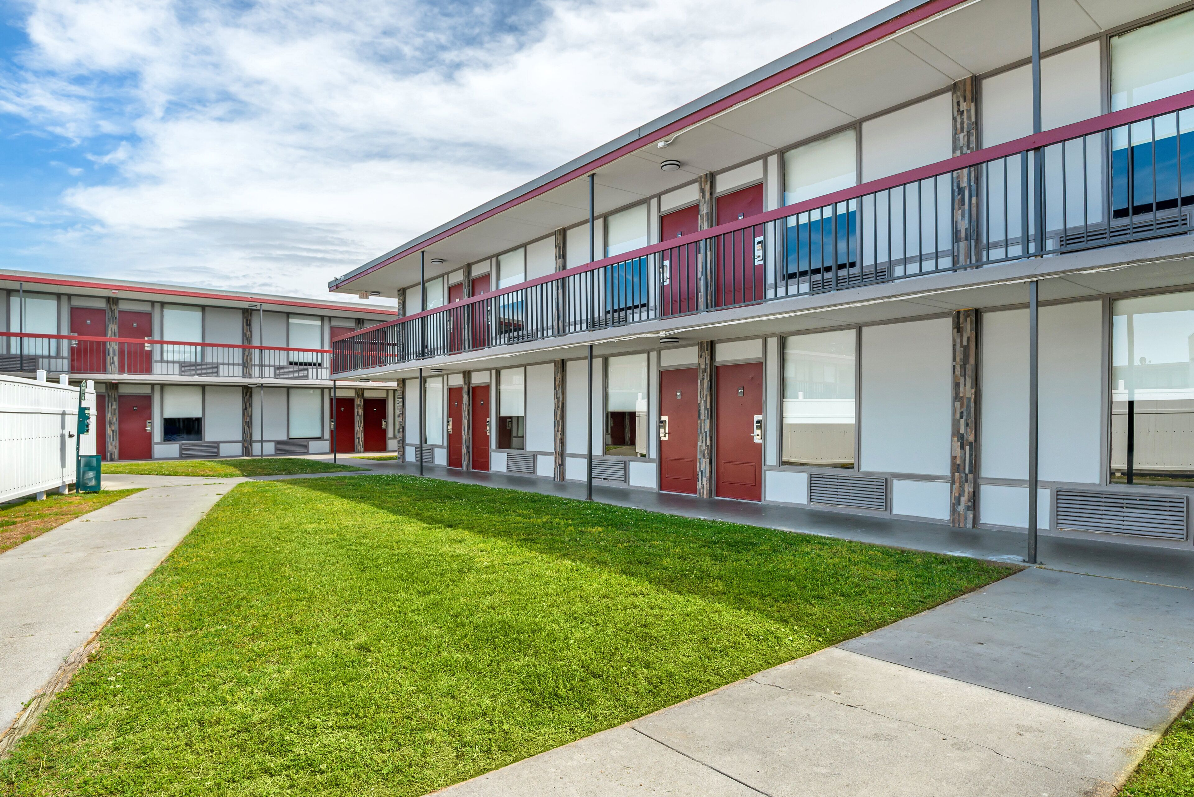 A modern multi-story building with a flat roof, large windows, and a well-maintained lawn.