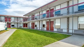 A modern multi-story building with a flat roof, large windows, and a well-maintained lawn.