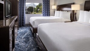 A hotel room with two beds, a television, a desk, and a window with curtains. - Isle Casino Hotel Lula Hotel & Casino - A Caesars Rewards Destination (Lula)