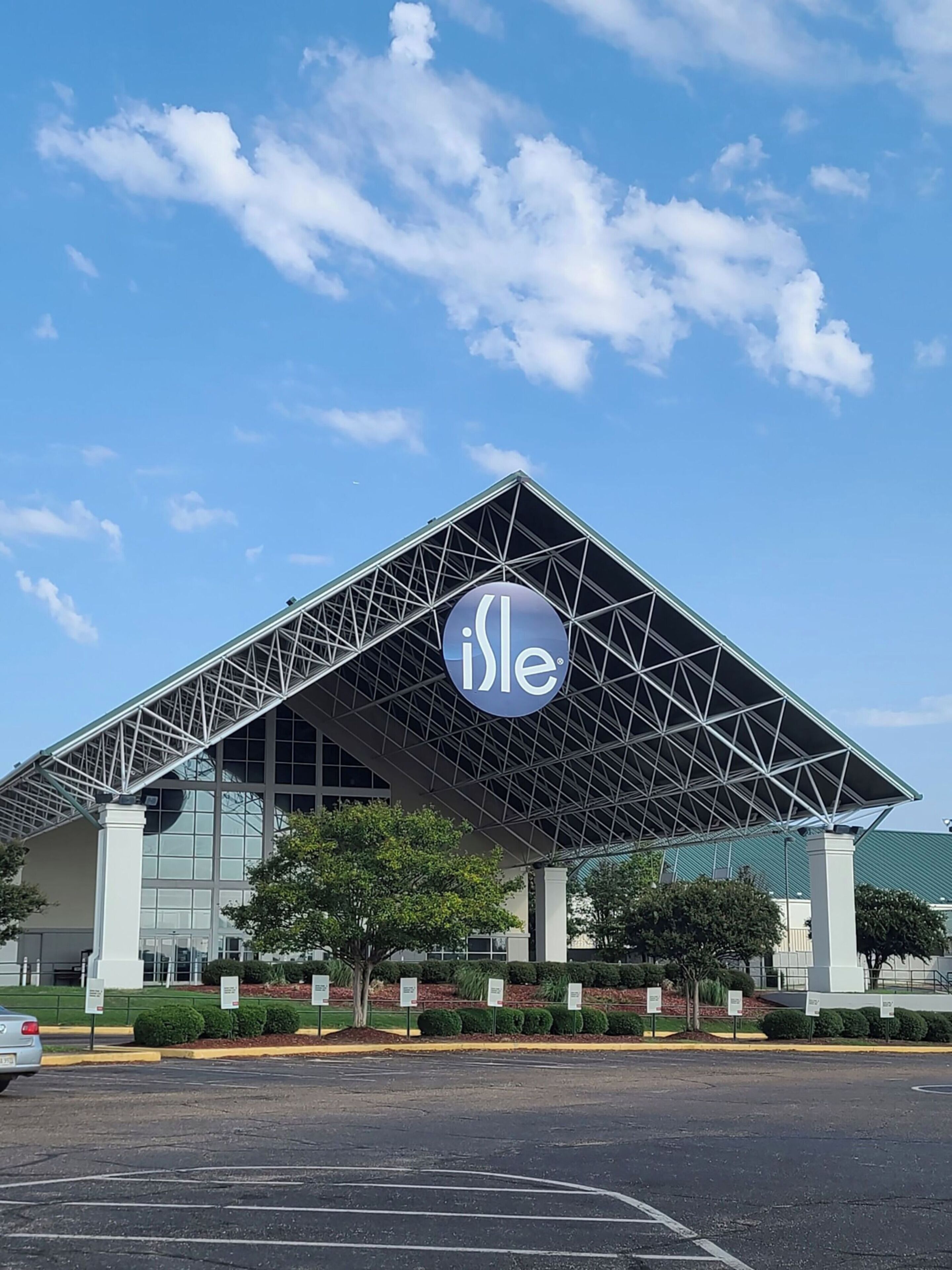Un edificio moderno con un gran logo 'ile' en el techo, rodeado por un estacionamiento y zonas verdes.