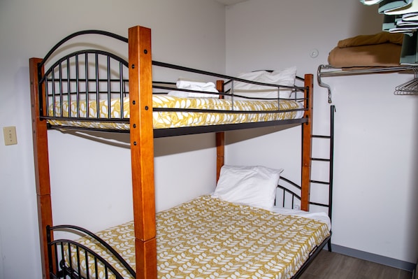 Uma cama de solteiro com um edredom estampado, estrutura de madeira e cabeceira de metal.