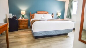 A hotel room with a bed, bedside tables, a coffee machine, and a lamp. - Spanish Villa Resort (Penticton)