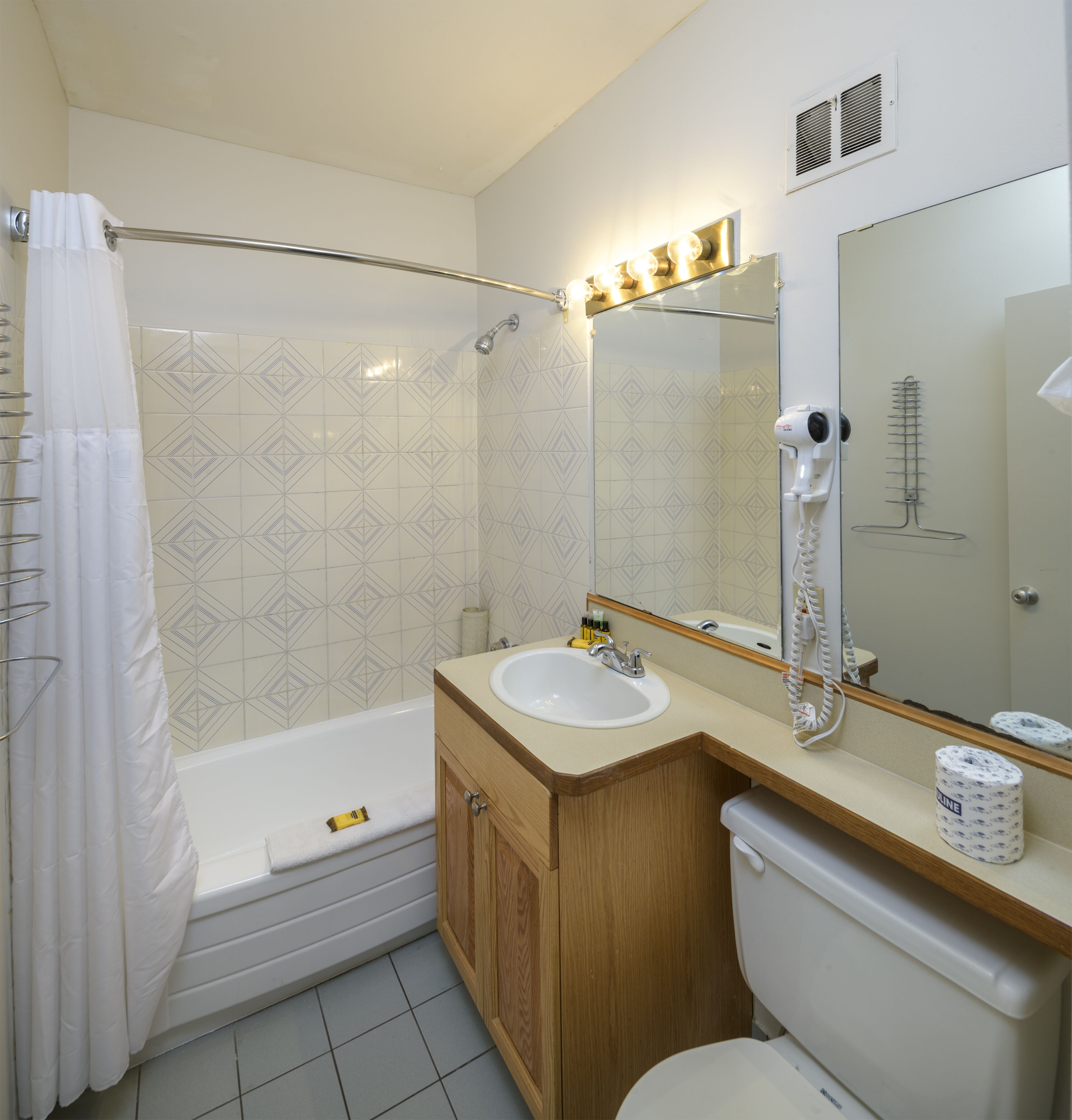 A bathroom with a bathtub, a sink, a toilet, a shower, and a hairdryer.
