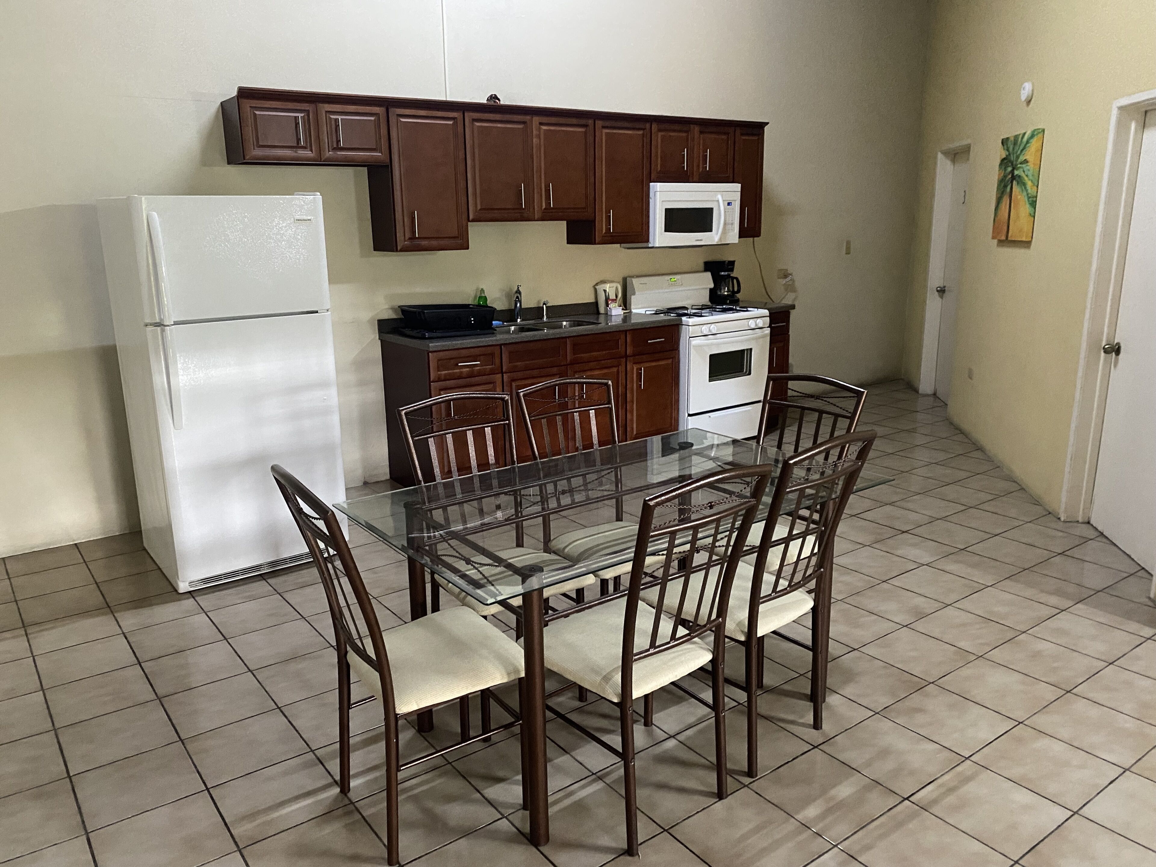 A compact kitchen with a refrigerator, microwave, stove, and a dining table with chairs.