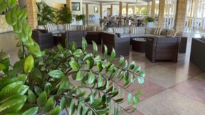 Un vestíbulo amplio con muebles de mimbre y plantas en macetas.