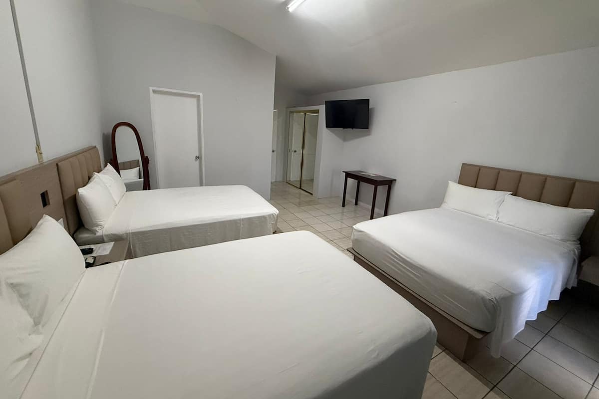 A hotel room with two beds, a TV, a mirror, and a door leading to a bathroom.