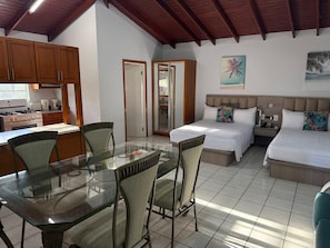 A hotel room with a bed, bedside table, and a glass dining table with chairs.