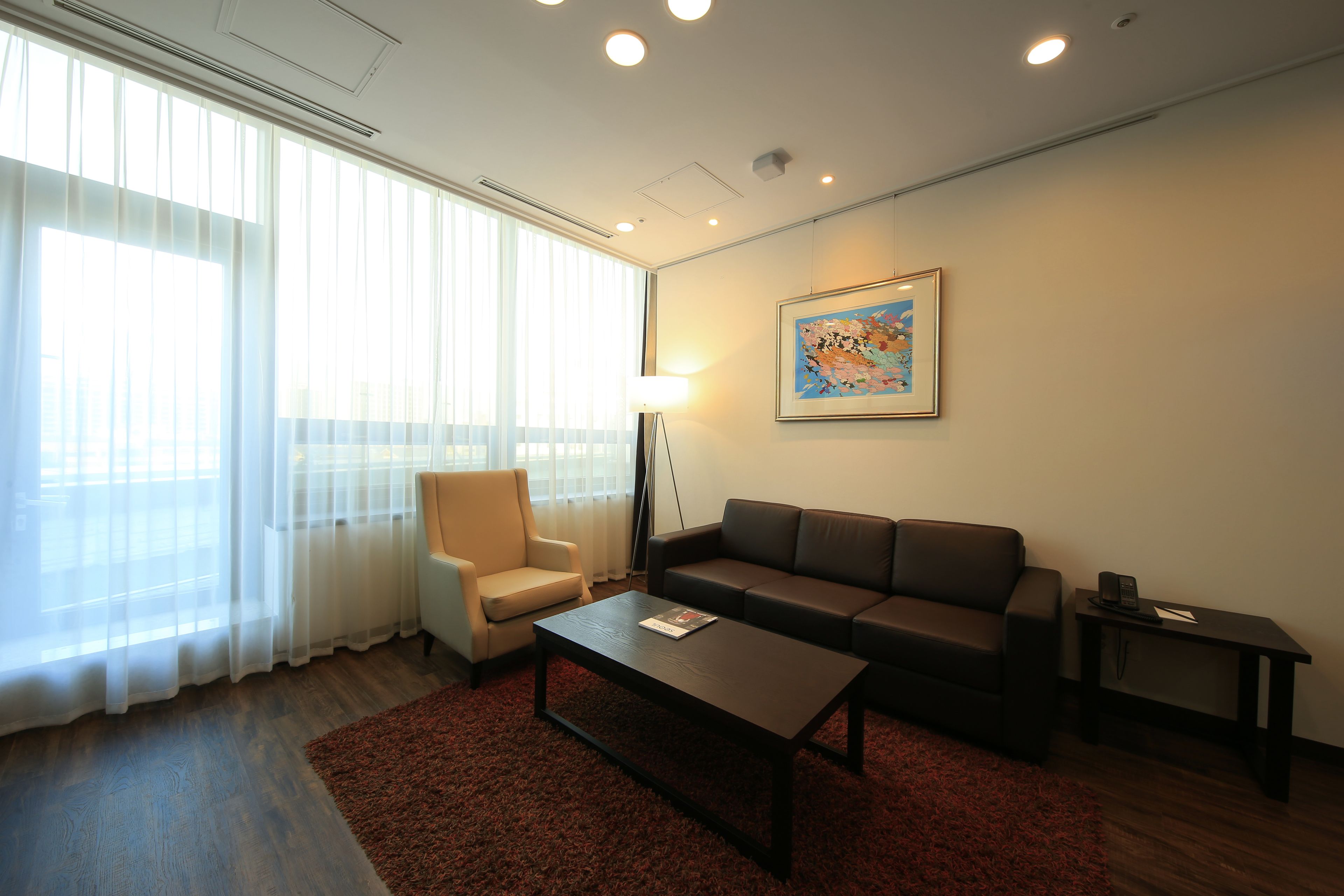A modern living room with a sofa, armchair, coffee table, and a lamp.