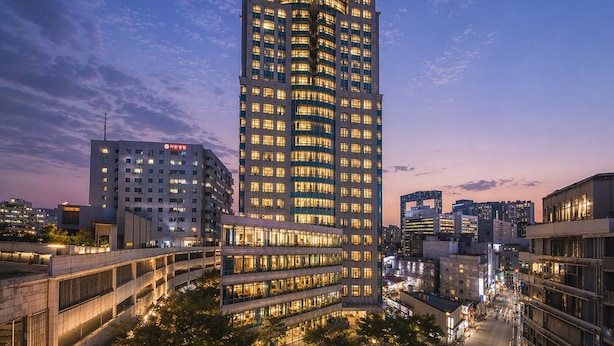 Un hotel de gran altura con varios pisos, ventanas iluminadas y una señalización destacada en la parte superior.