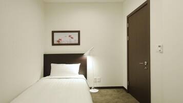 Une chambre d’hôtel avec un lit, une table de chevet, une lampe, une porte et un tableau encadré au mur.