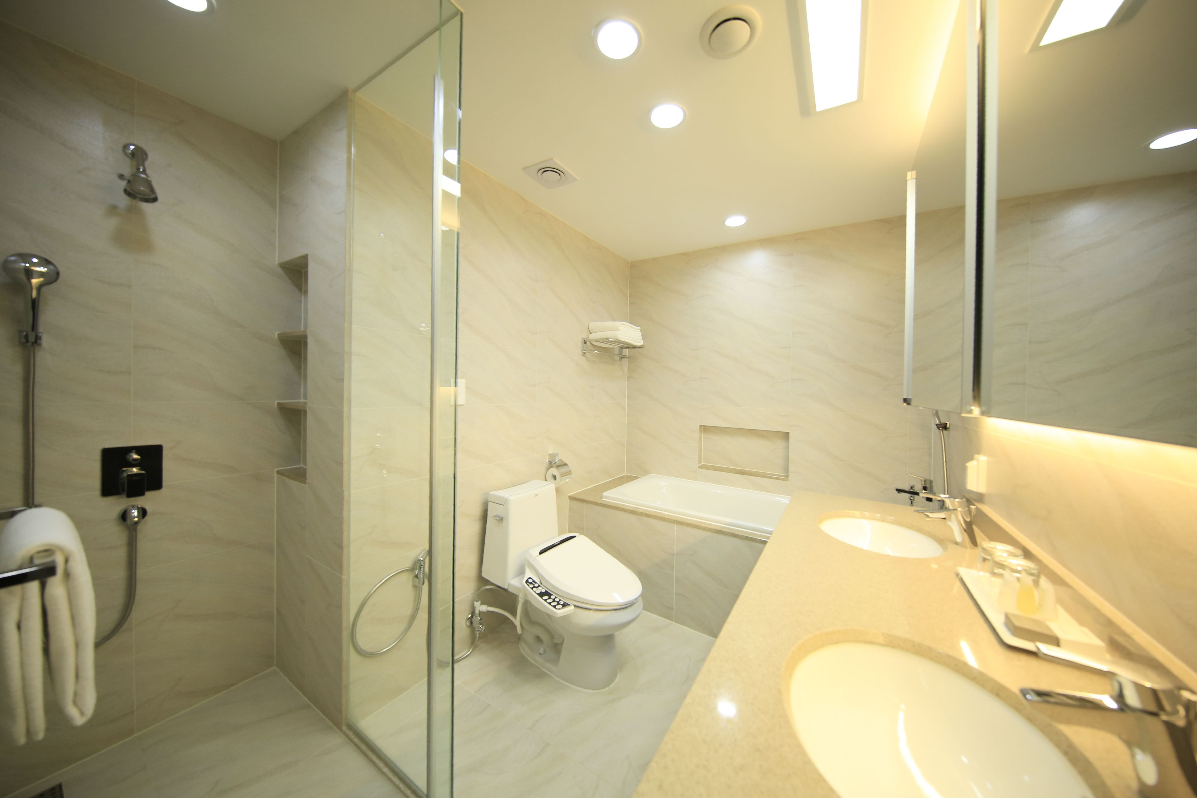 Un baño moderno con ducha envuelta en vidrio, inodoro y zona de lavamanos con espejo.