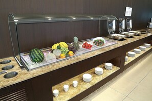 A buffet with a variety of fruits and vegetables, including watermelon, cantaloupe, pineapple, and grapes.