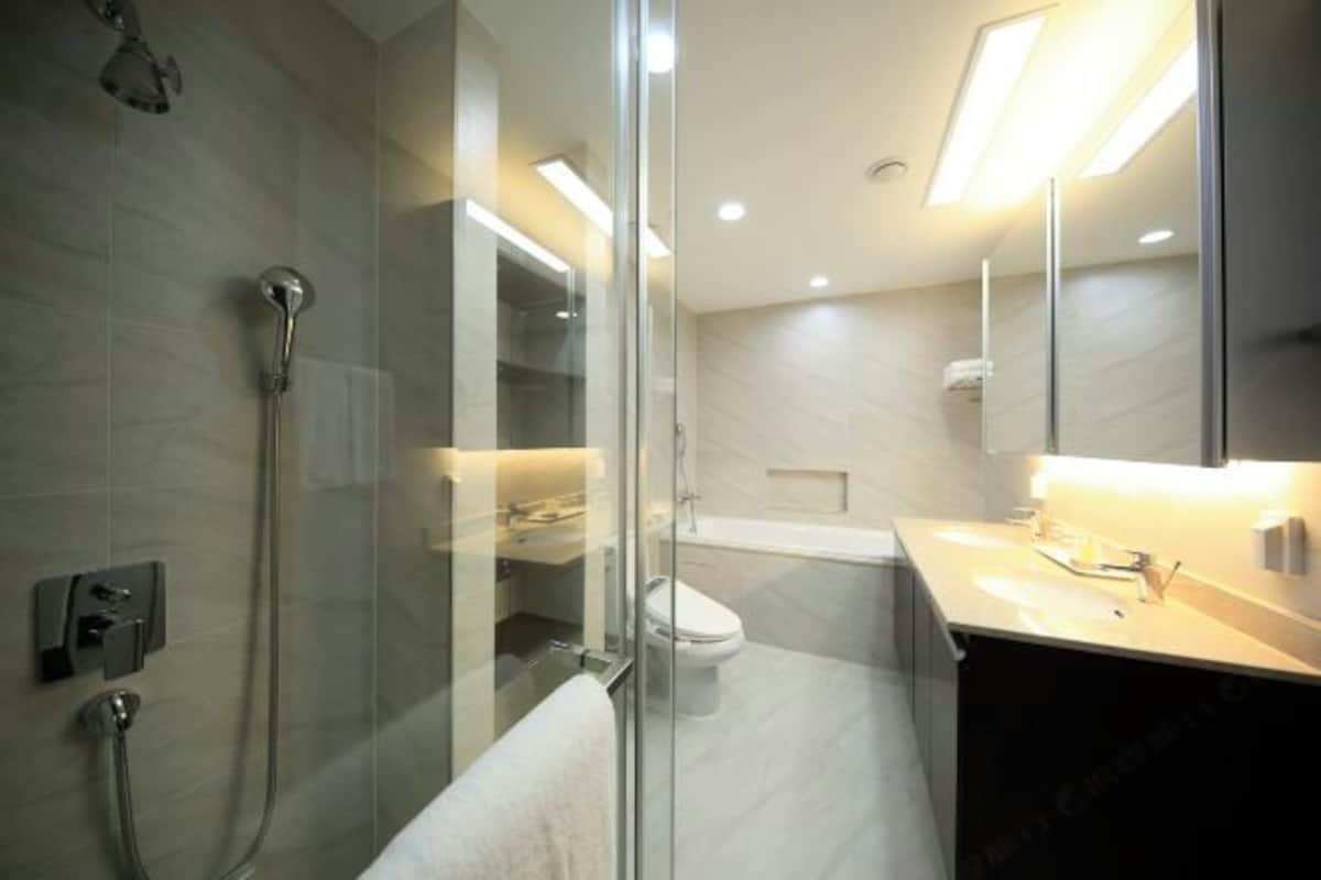 Un baño moderno con ducha de vidrio, inodoro y lavamanos con espejo.