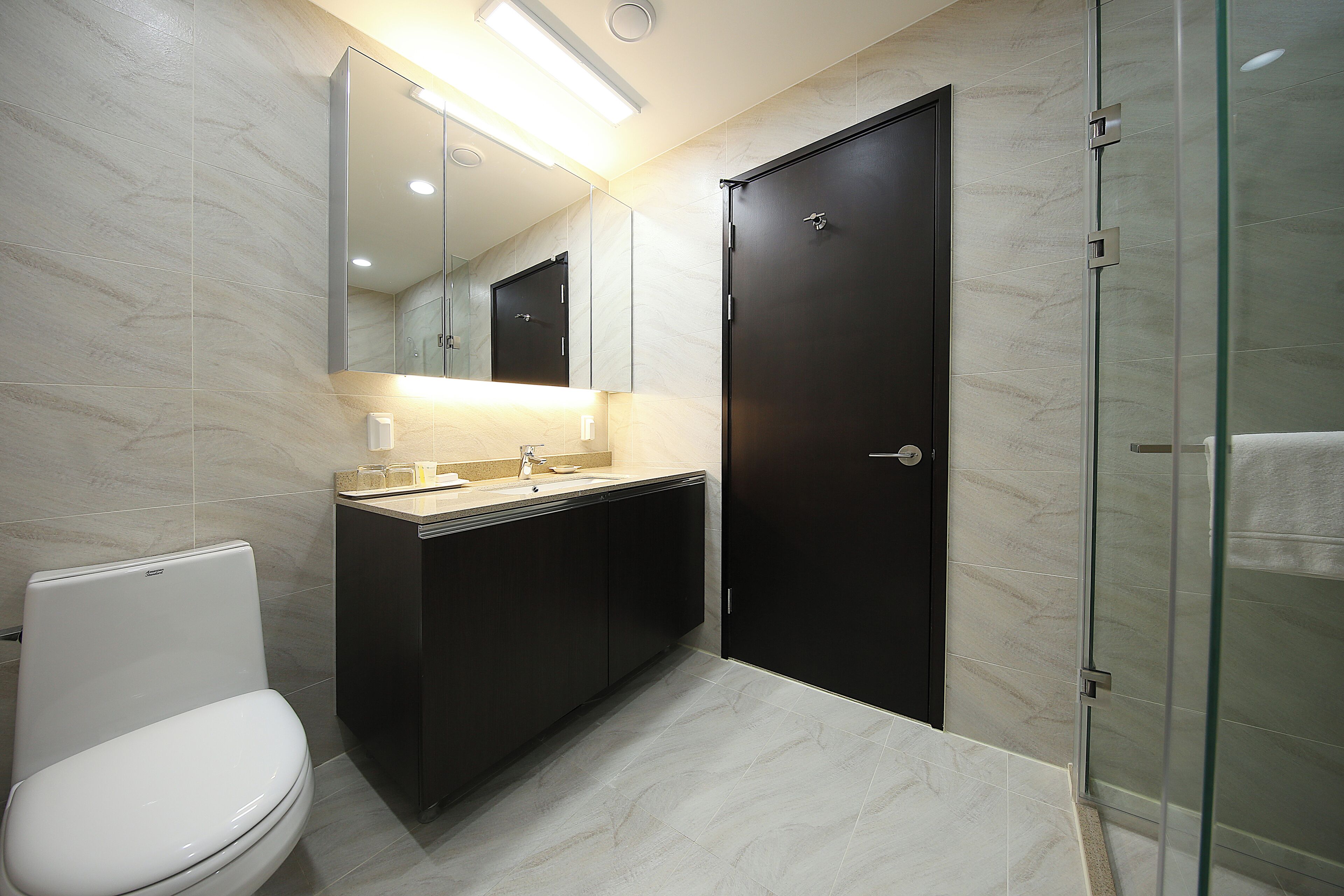 A modern bathroom with a toilet, sink, and mirror.